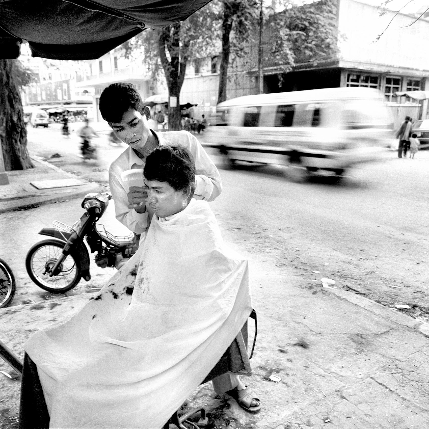 a-barber-in-angkor-wat-cuts-his-clients-hair-on-the-street