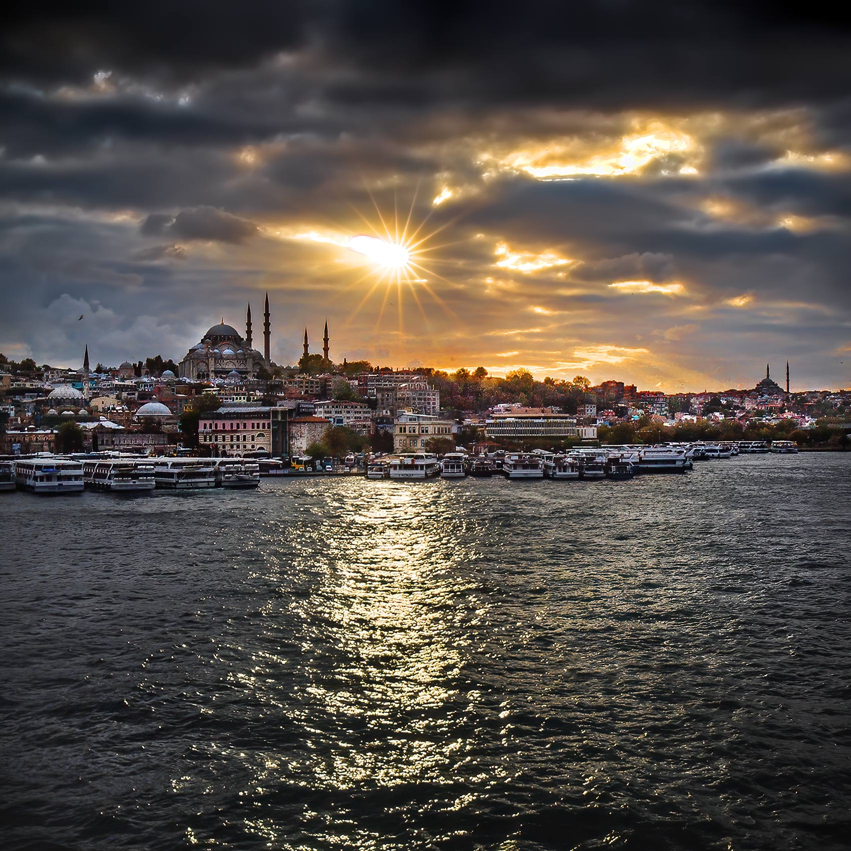 a-brilliant-sun-breaks-through-the-clouds-as-it-sets-over-the-historic-city-of-istanbul-