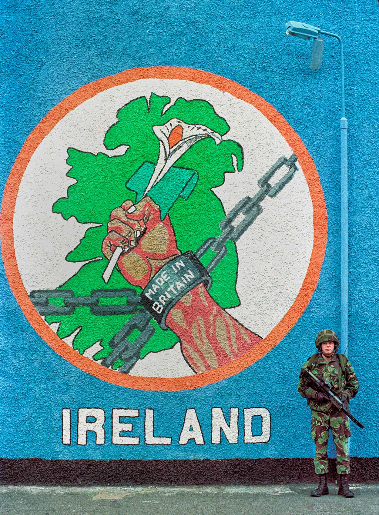 a british soldier stands in front a colourful mural in catholic west belfast during the troubles