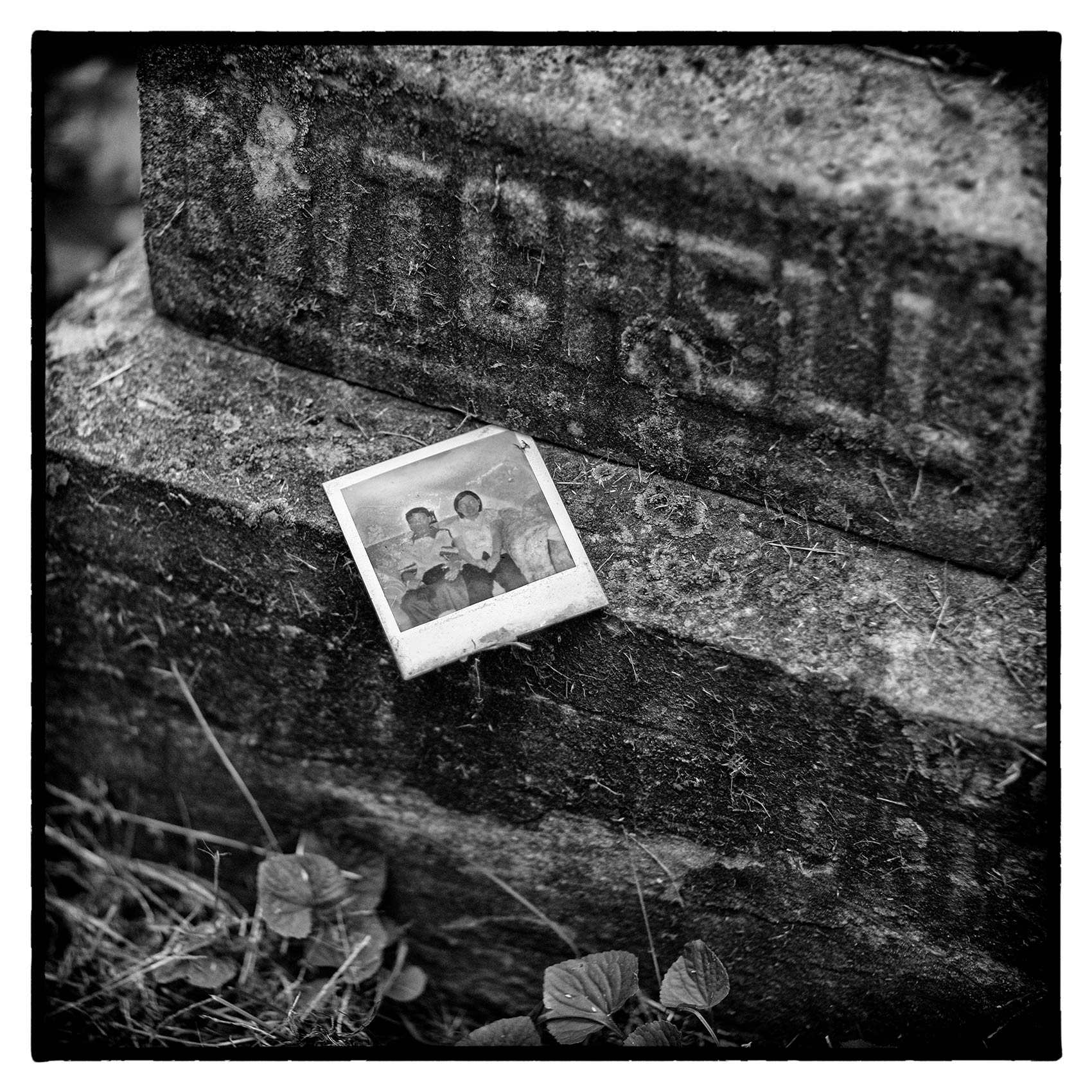 an old polaroid is attached to a stone grave at Torontos St. James Cemetary