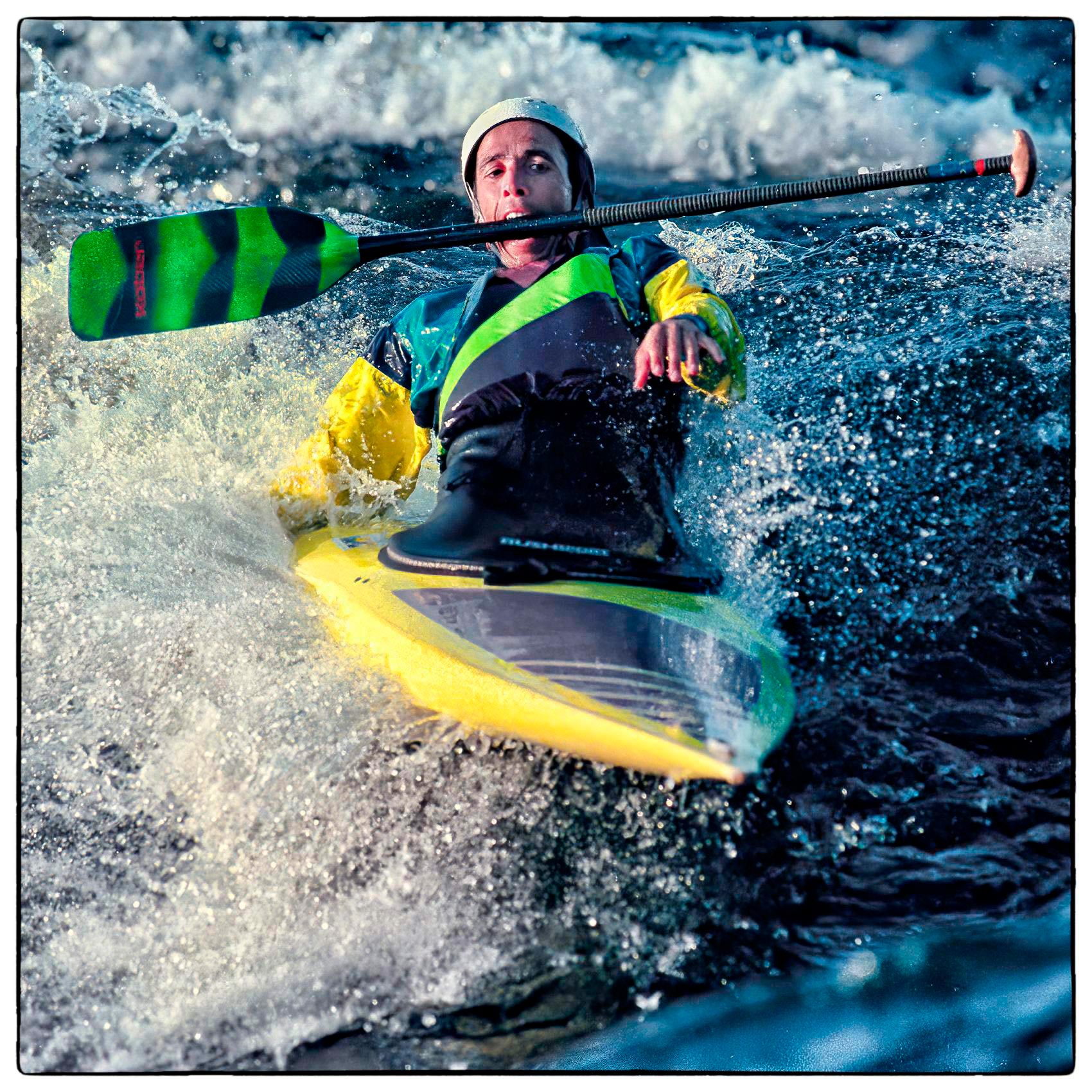 a-man-grimaces-as-he-kayaks-and-holds-his-paddle-in-his-mouth-as-he-surfs-the-waves-on-the-ottawa-river