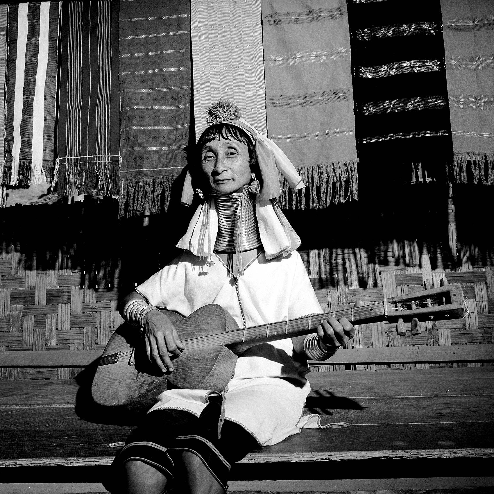 a-woman-from-the-red-karen-tribe-in-burma-plays-the-guitar-in-her-village-in-thailand