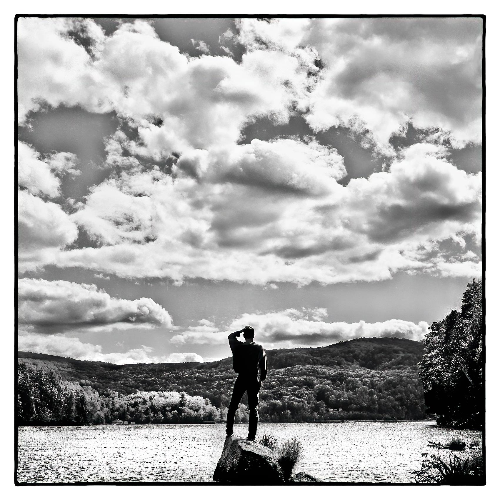 a-man-is-silhouetted-by-the-sun-as-he-stands-on-a-rock-on-meech-lake-in-gatineau-quebec-canada