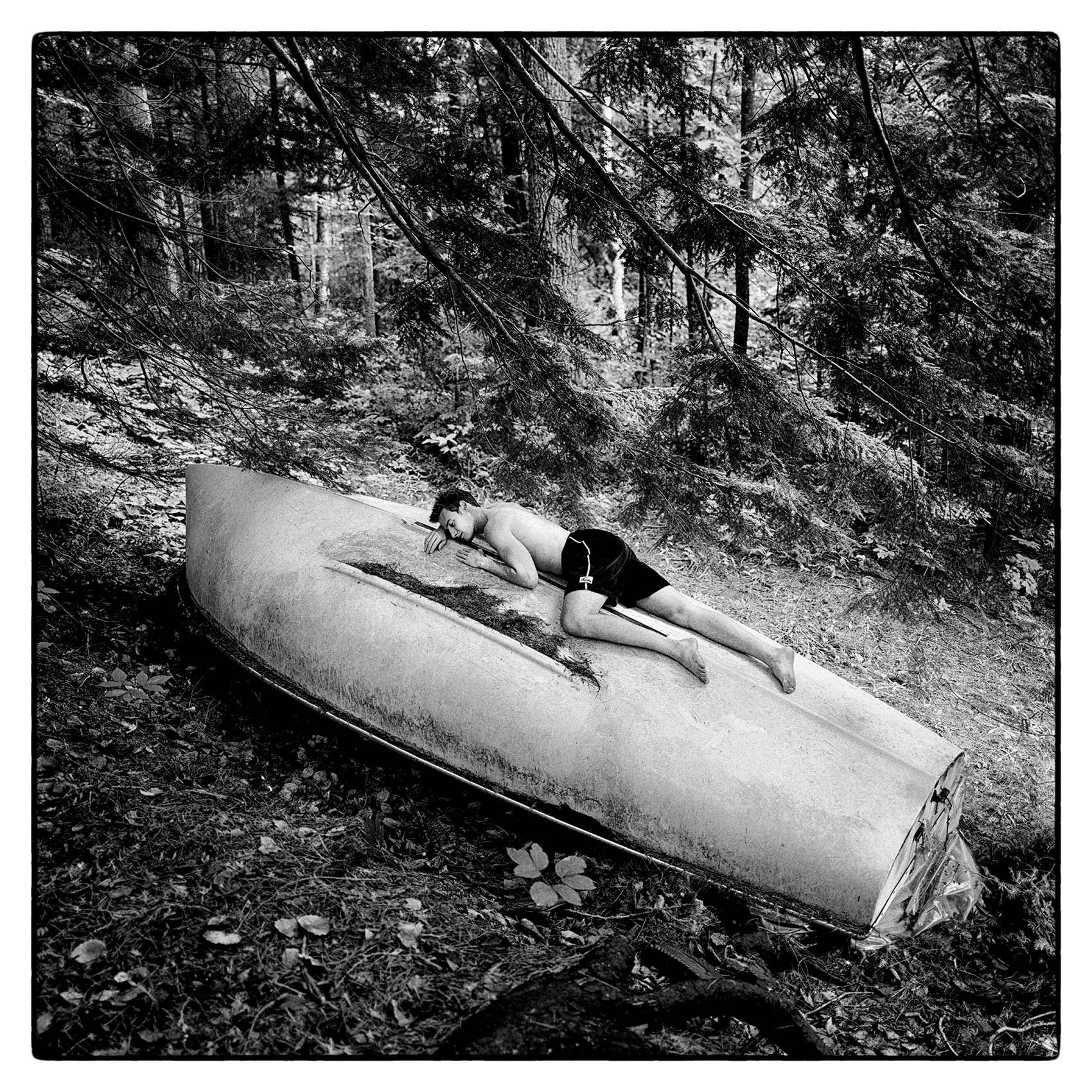a-man-lays-on-top-of-an-overturned-sailboat-in-the-sun-at-his-cottage-in-northern-ontario