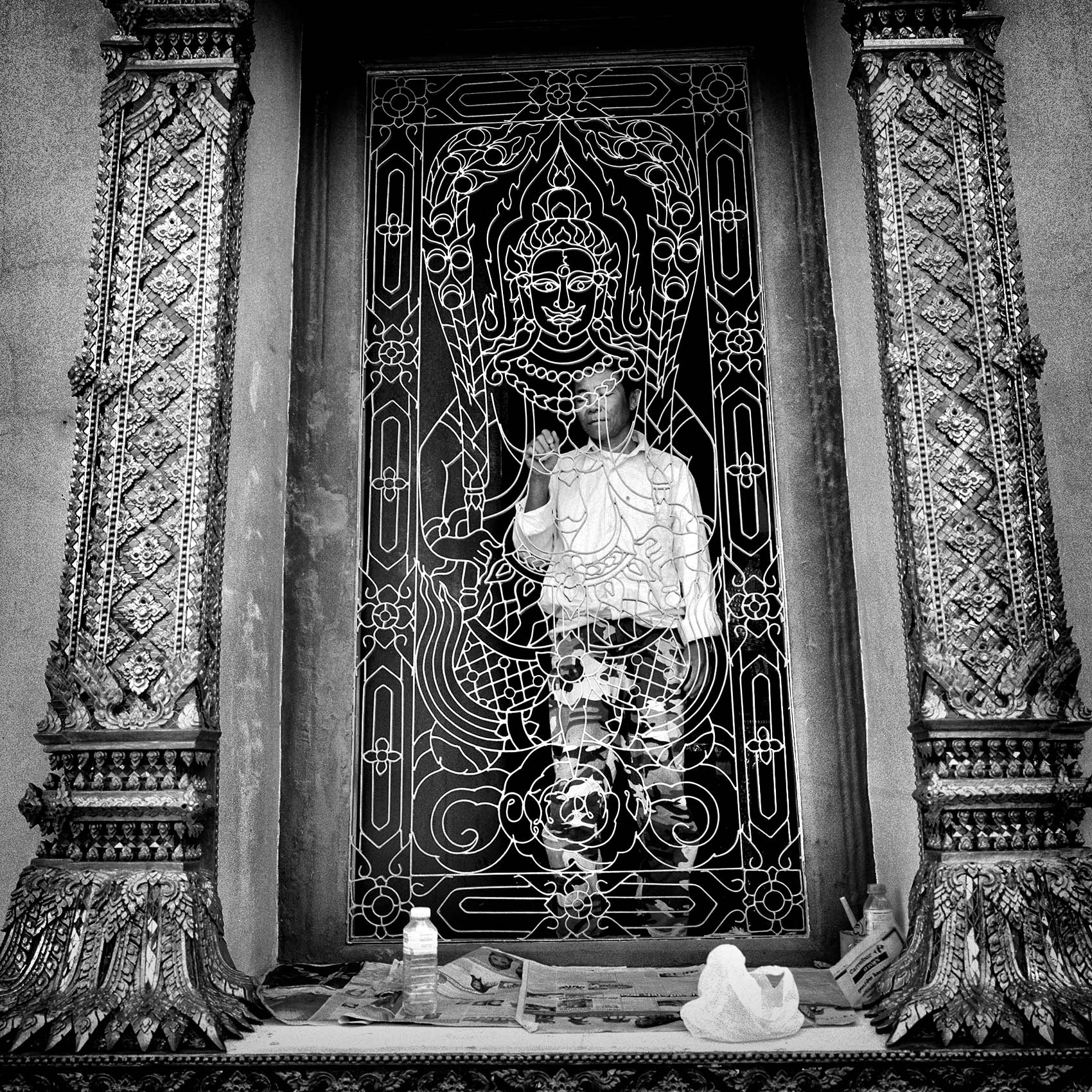 a-man-pauses-as-he-paints-an-gold-iron-gate-at-a-buddhist-temple-in-bangkok-thailand