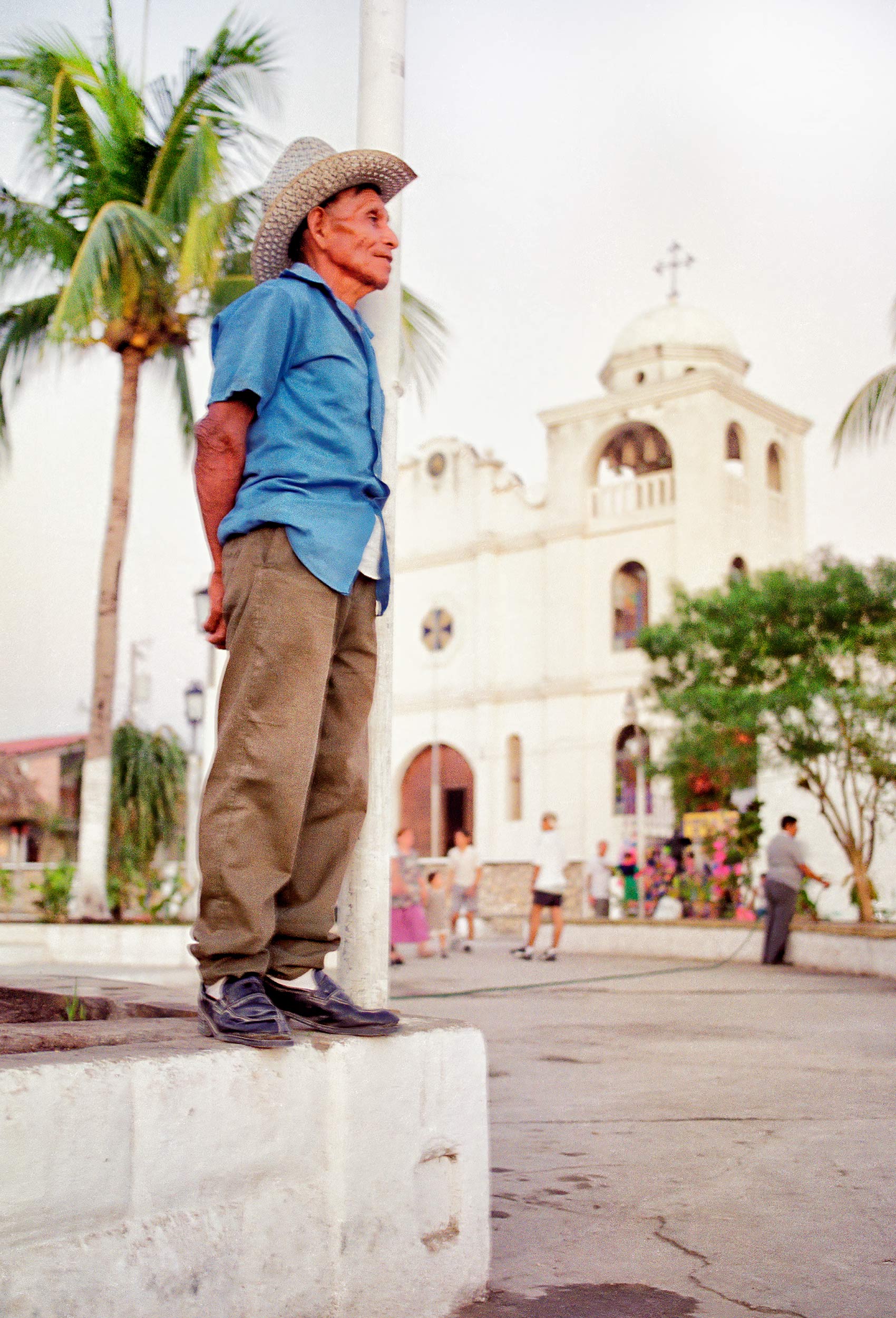 a-man-stands-near-a-church-at-sunset-in-flores-guatemala
