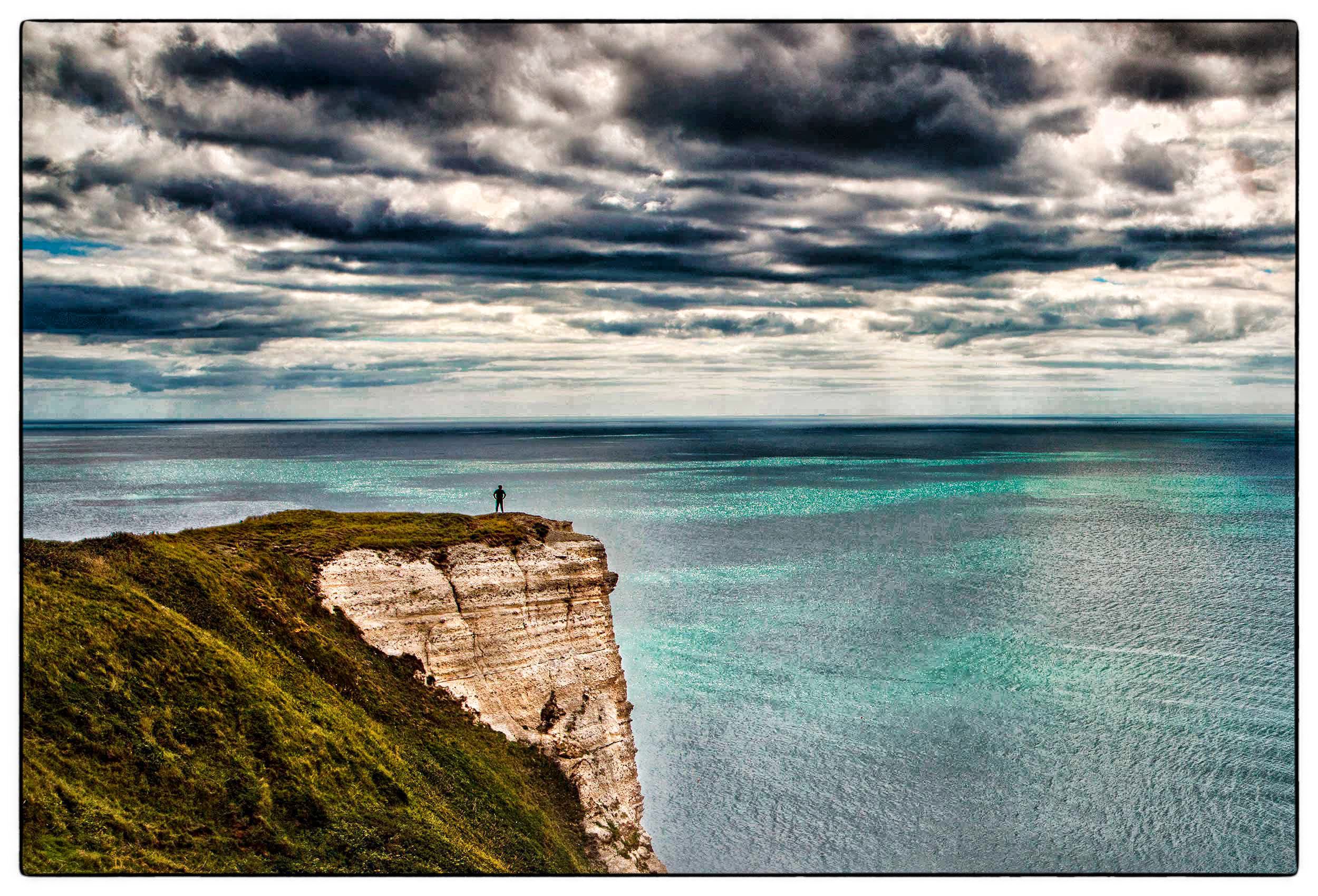 a-man-stands-on-a-cliff-near-lyme-regis-along-the-coastal-path-in-southwest-england