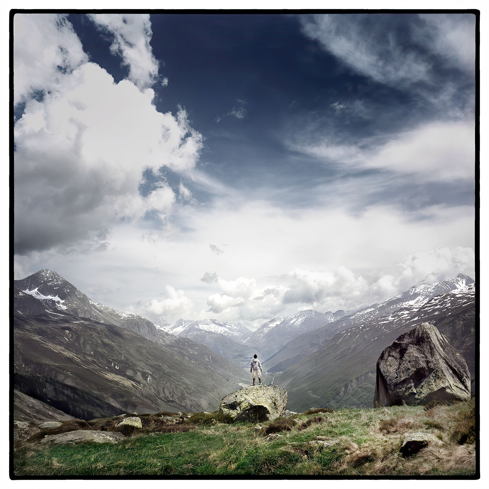 a-lone-man-stands-on-a-hillside-in-a-valley-looking-out-on-the-swiss-alps