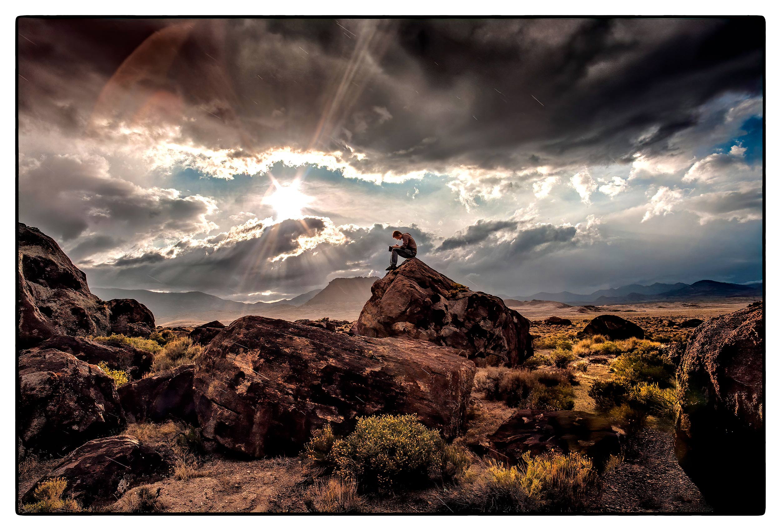 a-man-writes-in-his-journal-as-he-sits-on-a-rock-at-a-rest-stop-in-the-nevada-desert