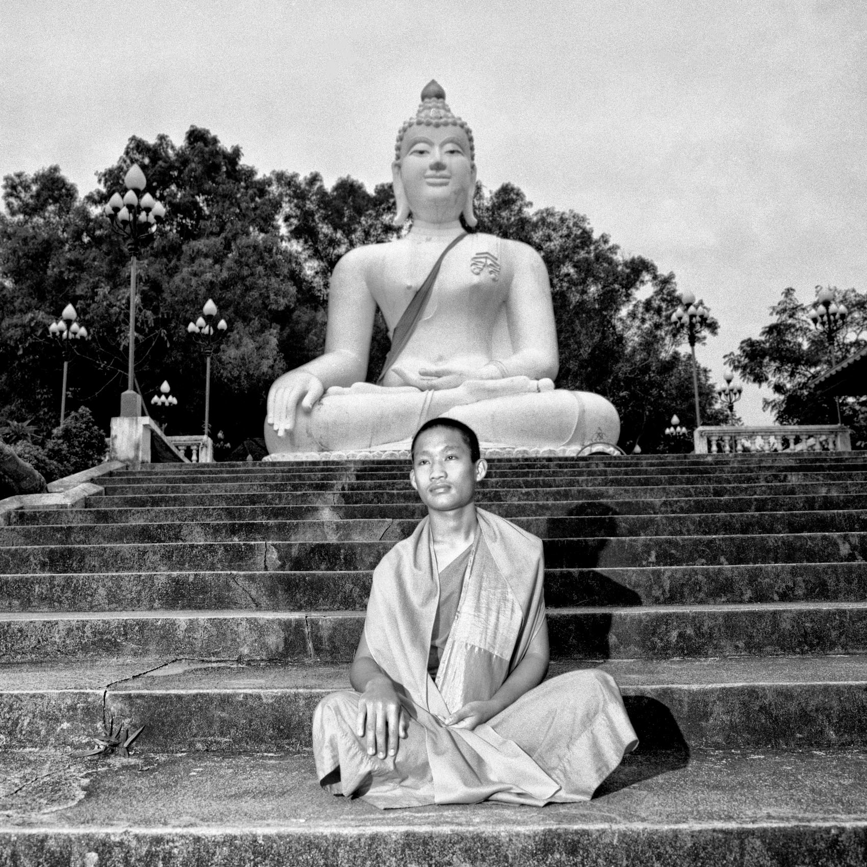 a-monk-copies-the-buddha-statue-behind-him-while-posing-for-a-photo-in-chang-rai-thailand