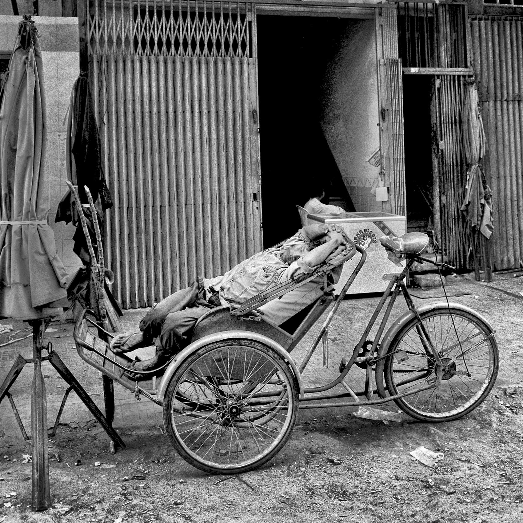 a-pedicab-driver-takes-a-nap-while-on-a-break-on-the-streets-of-phnom-penh-cambodia