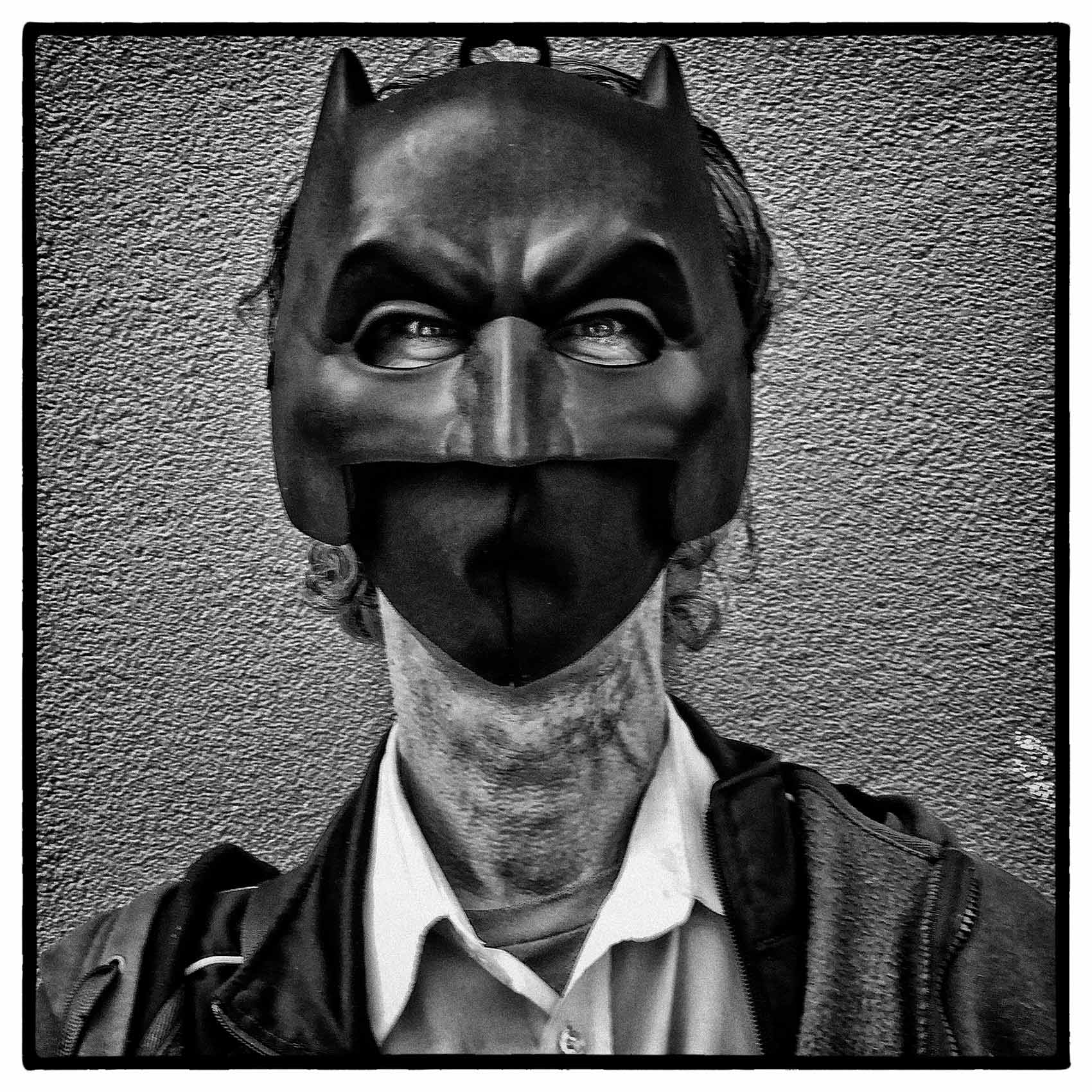 a man wearing a batman face mask stares intently during a toronto portrait by john hryniuk