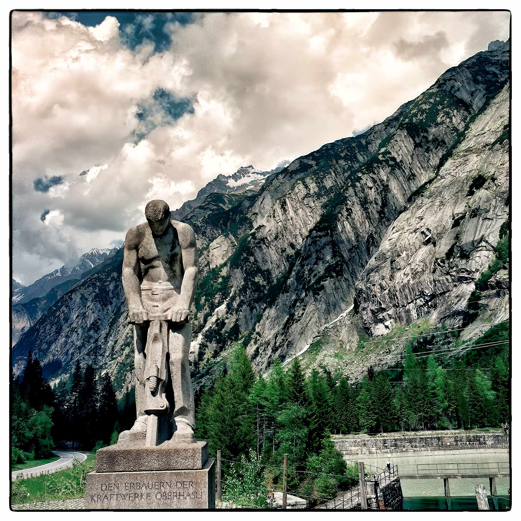 a-statue-of-a-construction-worker-stands-near-an-automobile-tunnel-in-the-swiss-alps