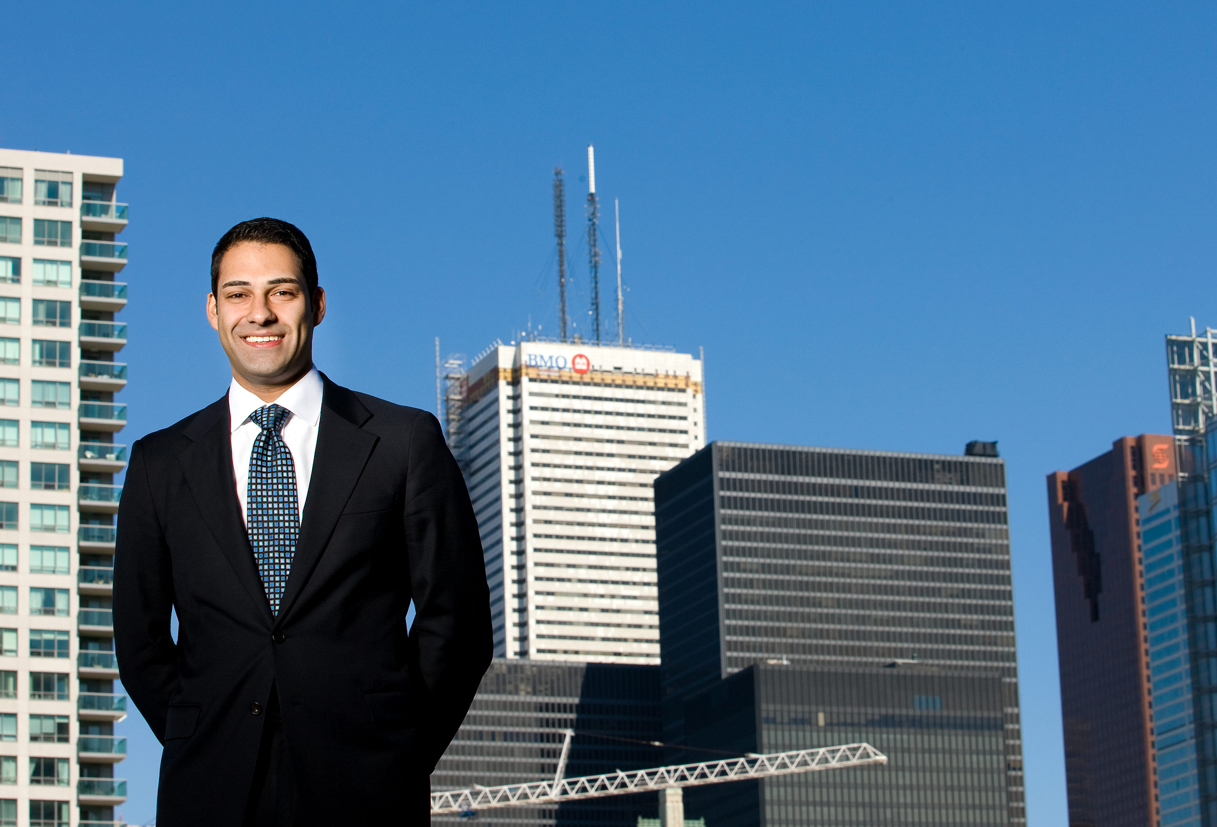 a graduate from the rotman school poses for his corporate photo in front of the toronto skyline