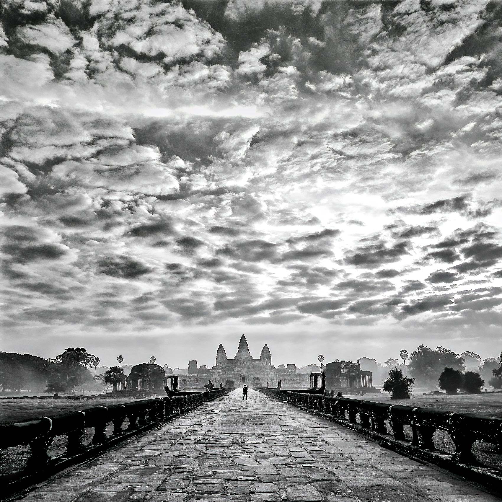 a tourist backpacker walks the pathway at sunrise leading to angkor wats famed temple in siem reap cambodia