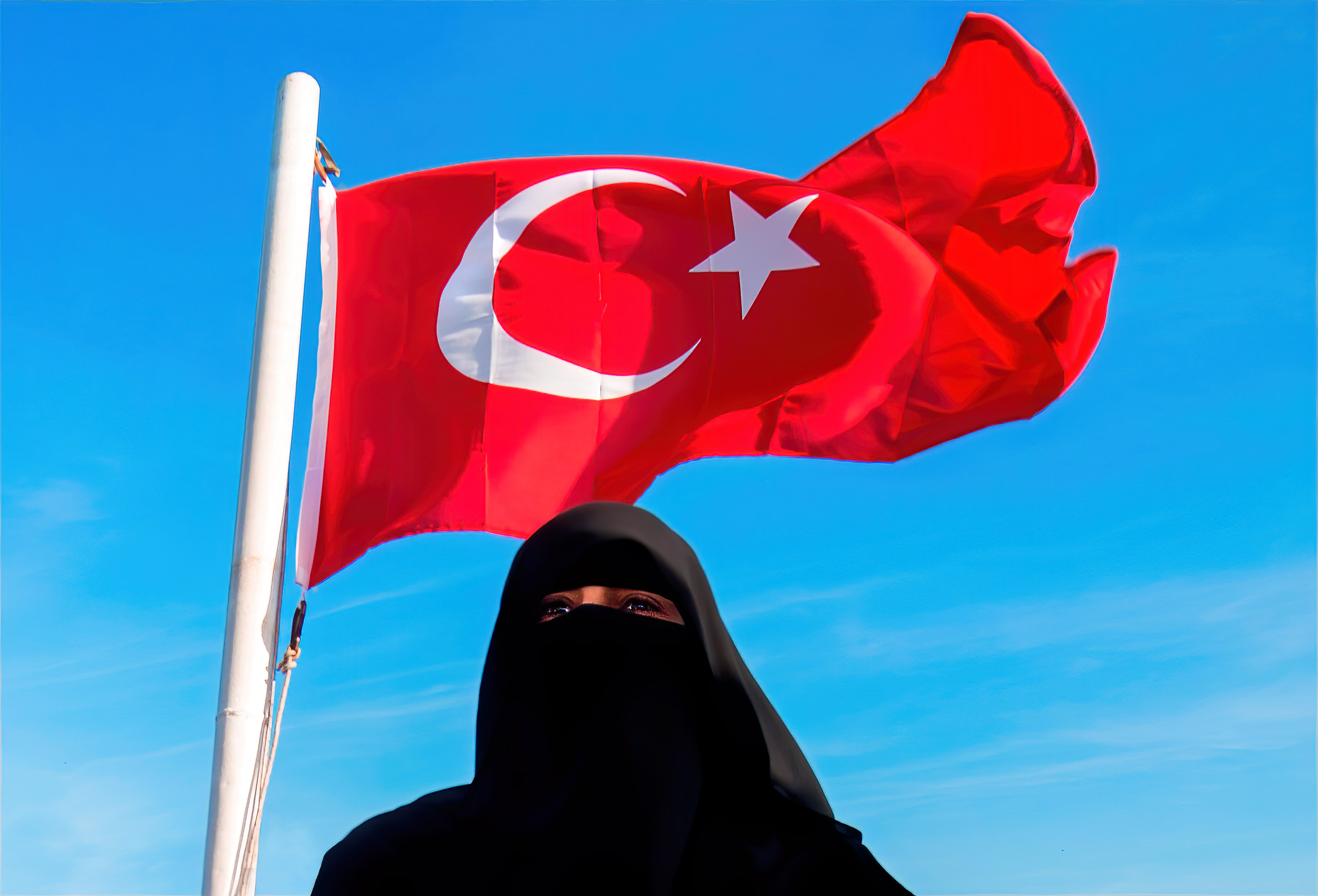 a turkish flag blows in the wind behind a muslim woman wearing a burqua in istanbul