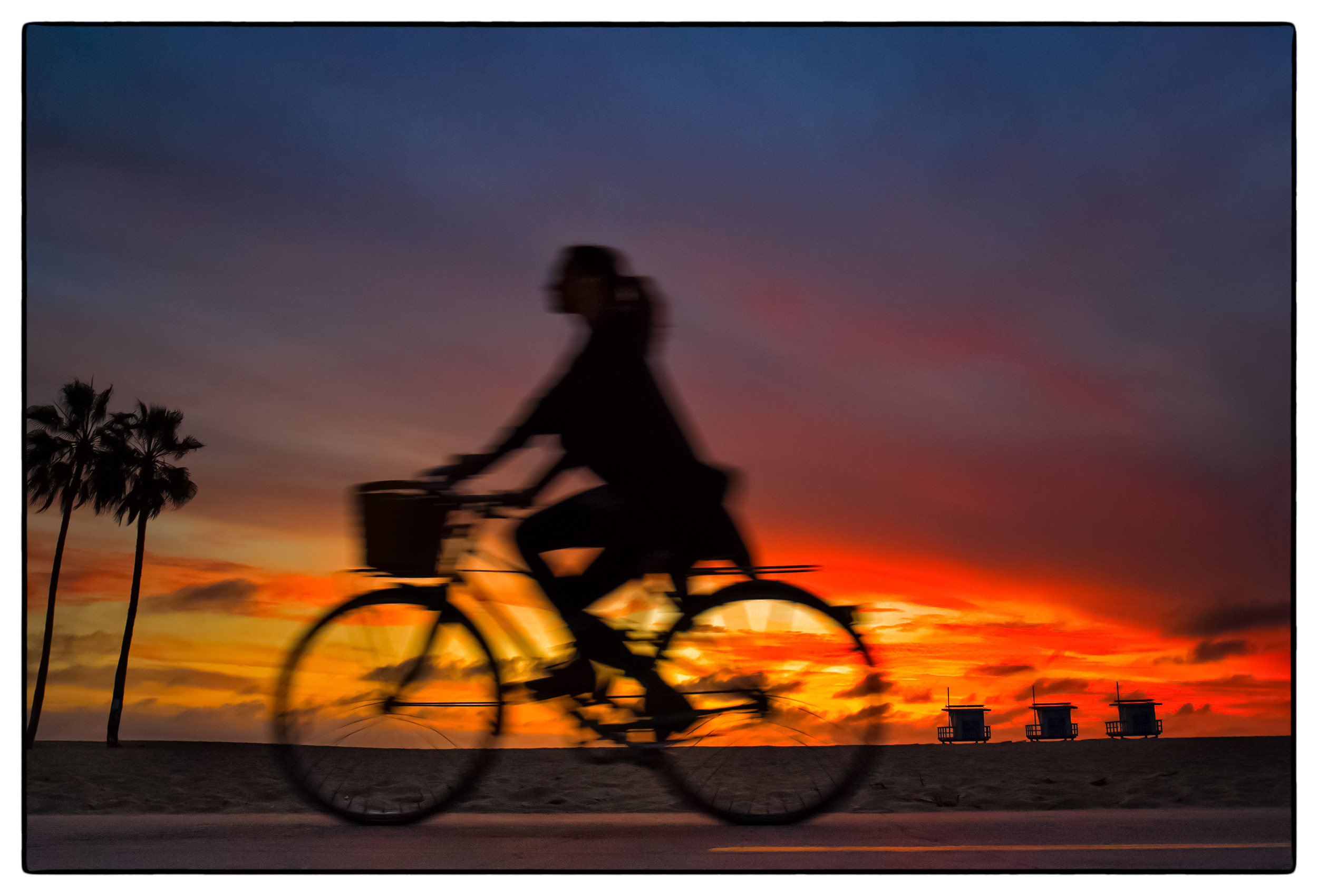 a-woman-on-her-bicycle-at-sunset-on-a-pathway-in-santa-monica-california