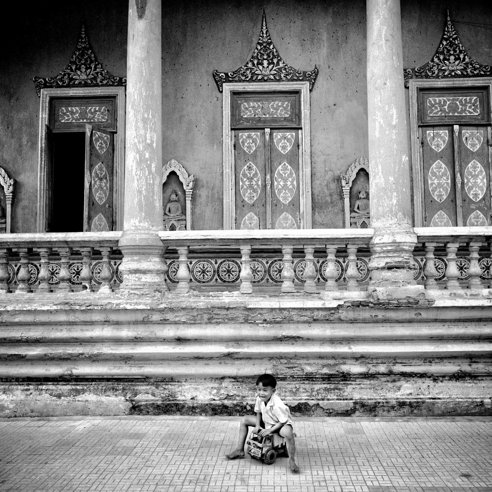a-young-boy-plays-on-his-toy-truck-outside-a-buddhist-temple-in-bangkok-thailand