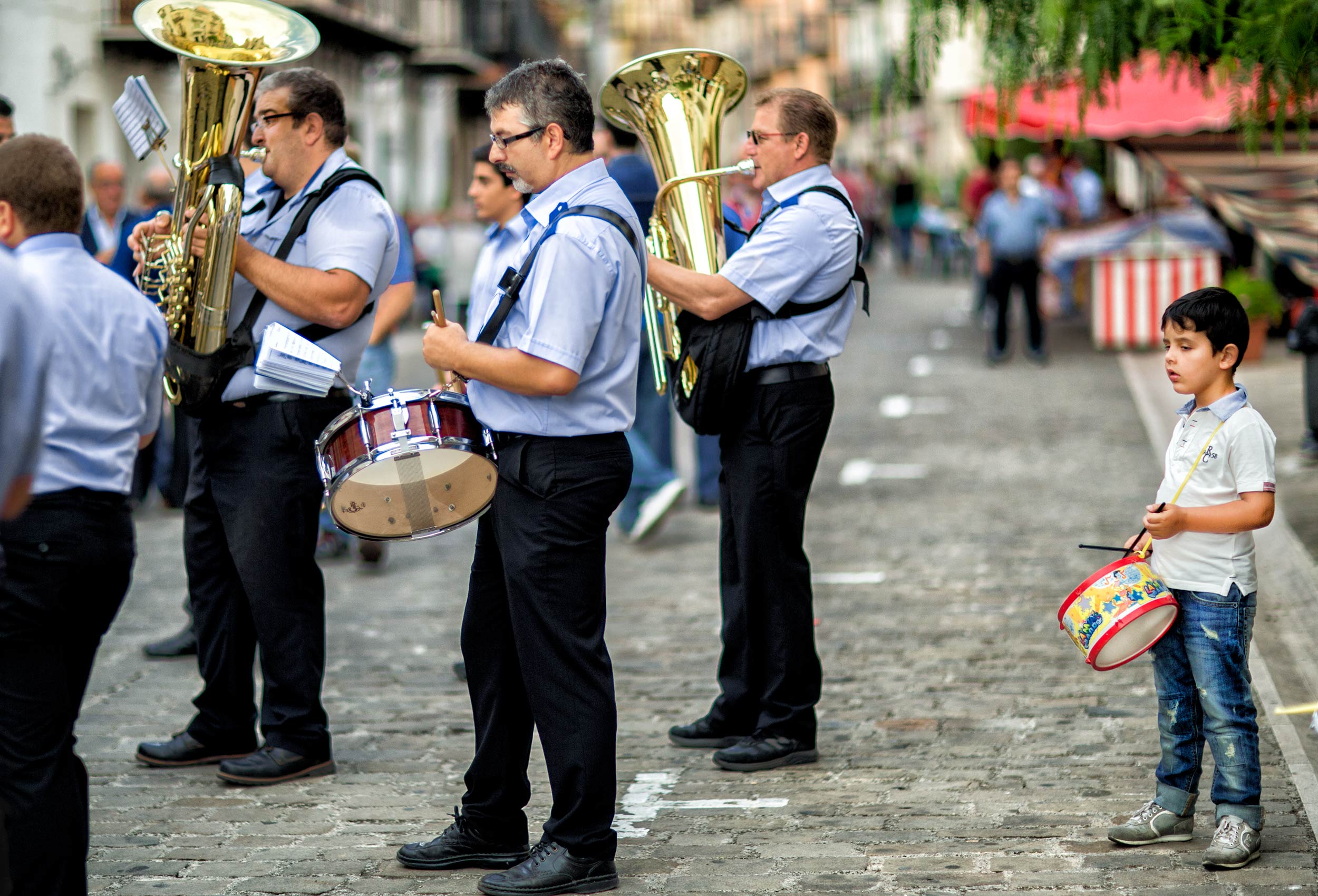 a-young-boy-with-his-toy-drum-joins-a-professional-band-on-the-streets-of-graterri-sicily