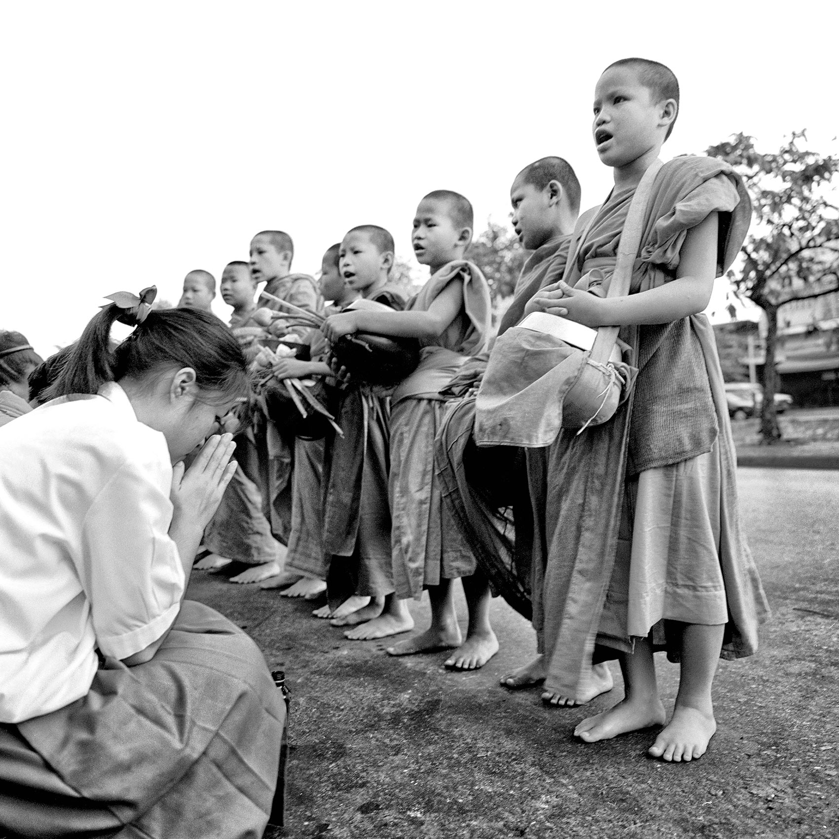 a-young-girl-bows-before-a-group-of-very-young-monks-on-a-street-in-northern-thailand