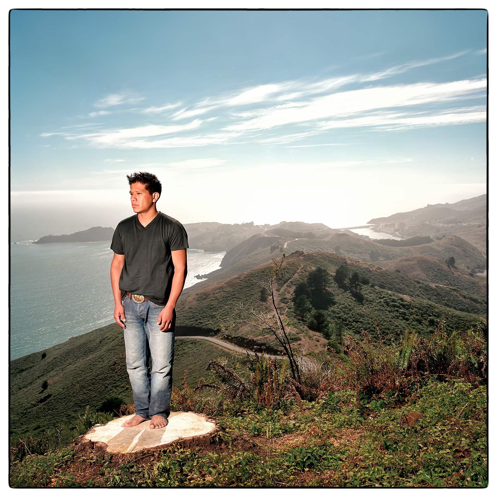 a-young-man-stands-on-a-wood-stump-as-he-looks-out-over-san-francisco-bay
