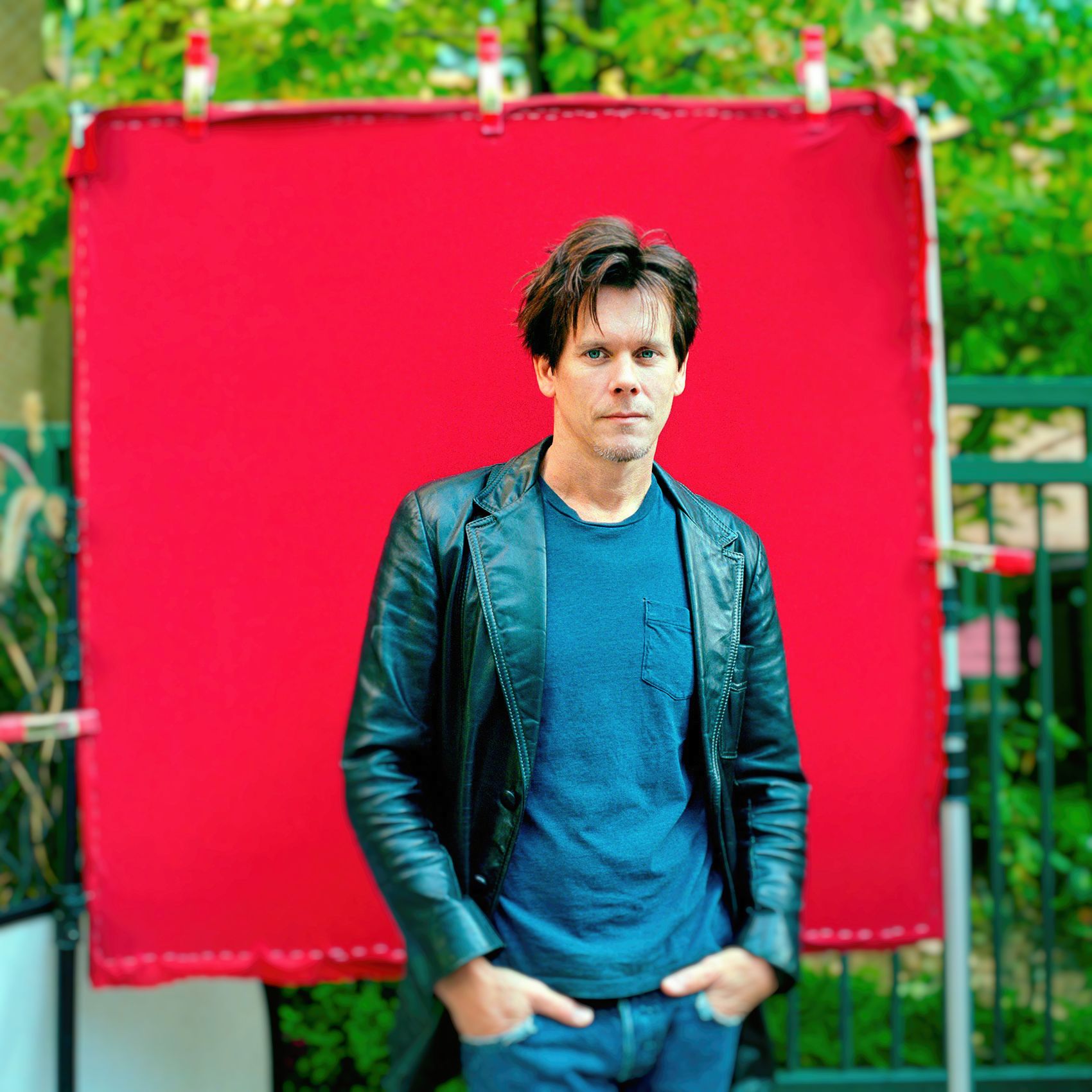 actor kevin bacon poses for a casual photo against a red background at tiff in toronto