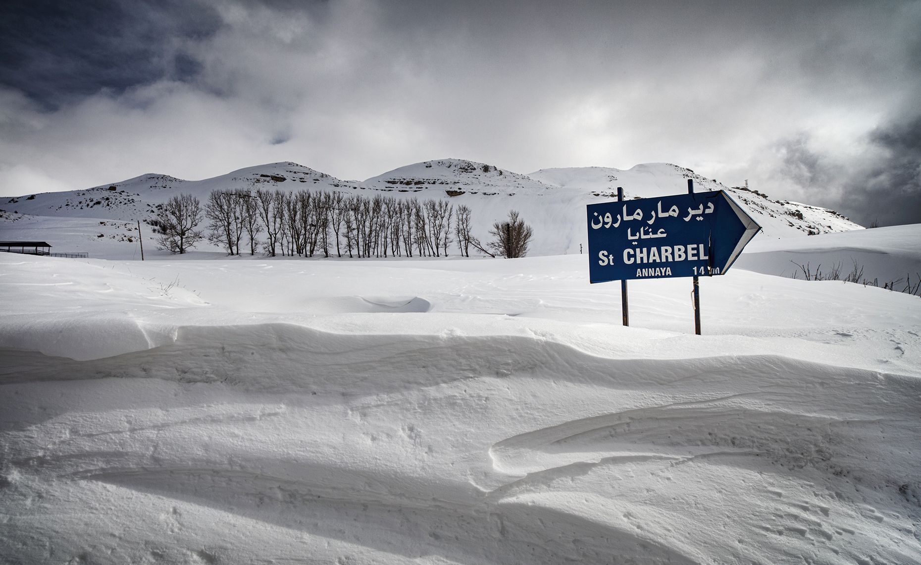a destination sign by the side of the road in the snow covered mountains above byblos lebanon