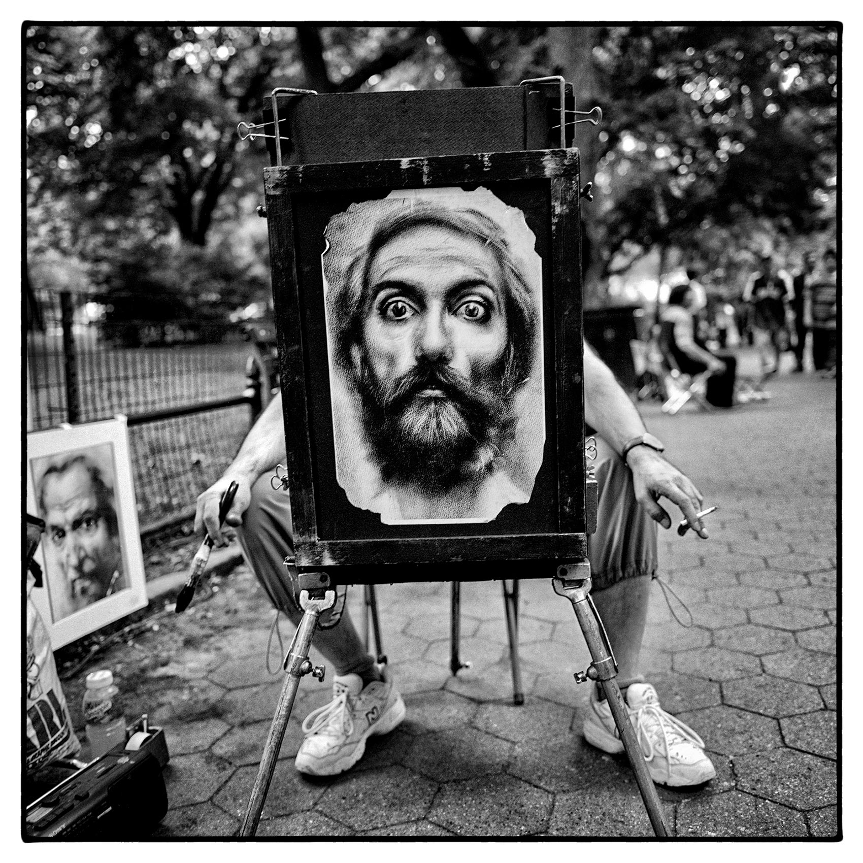 an-artist-in-central-park-in-new-york-sits-behind-a-painting-of-a-face