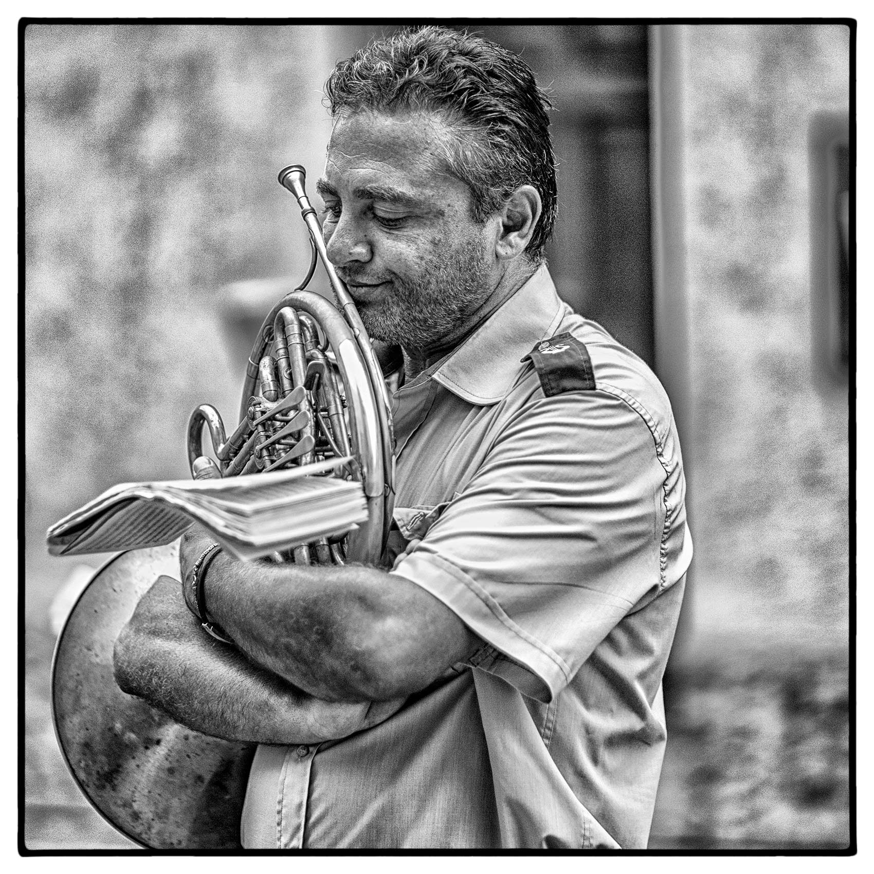 an-italian-man-holds-his-french-horn-tightly-as-he-appears-deep-in-thought-while-reading-his-music