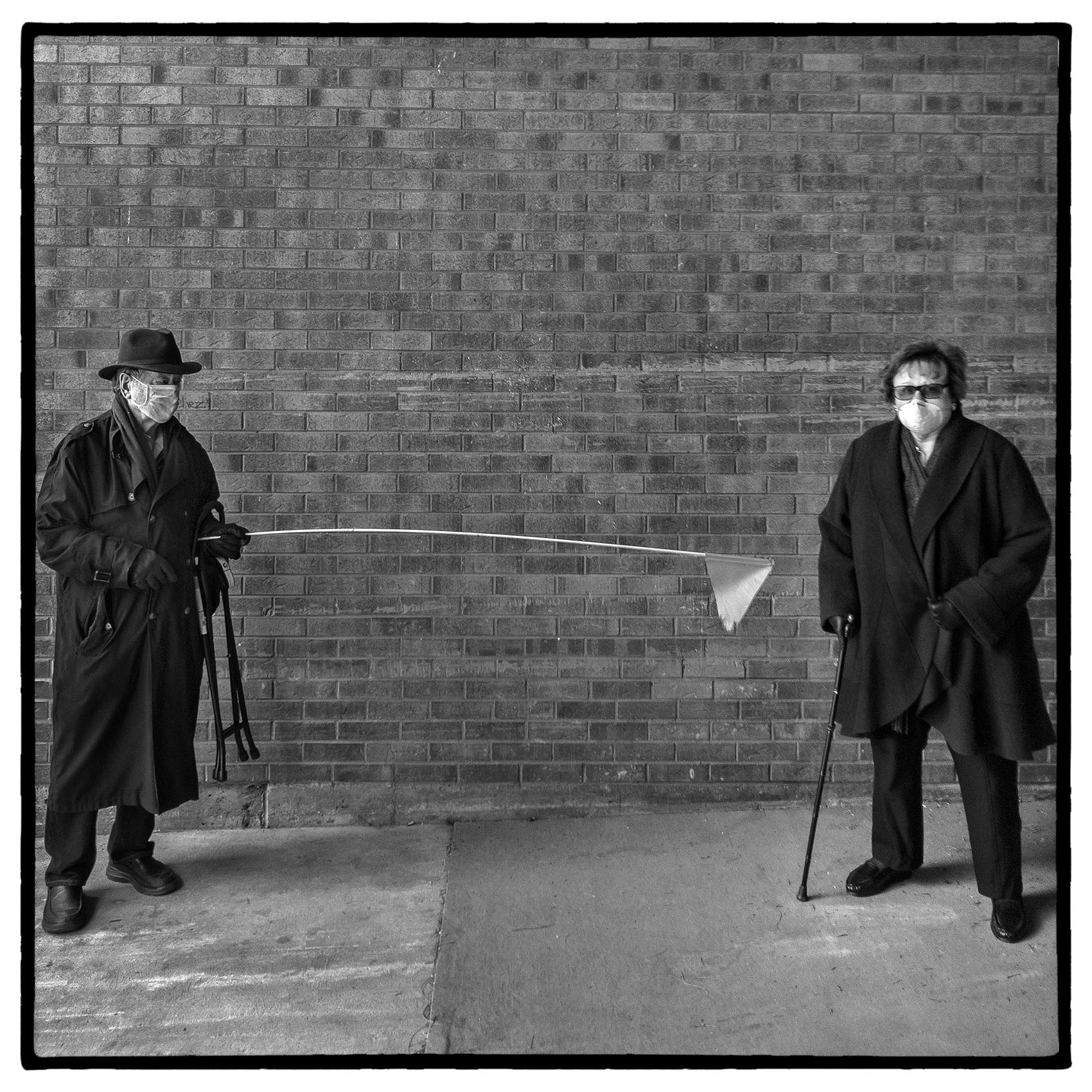 a man holds up his social distancing stick next to his friend during the pandemic in toronto
