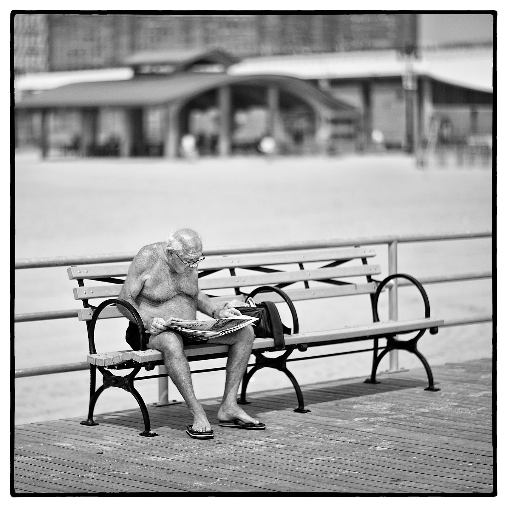 an-old-man-reads-a-newspaper-on-a-bench-in-coney-island-new-york