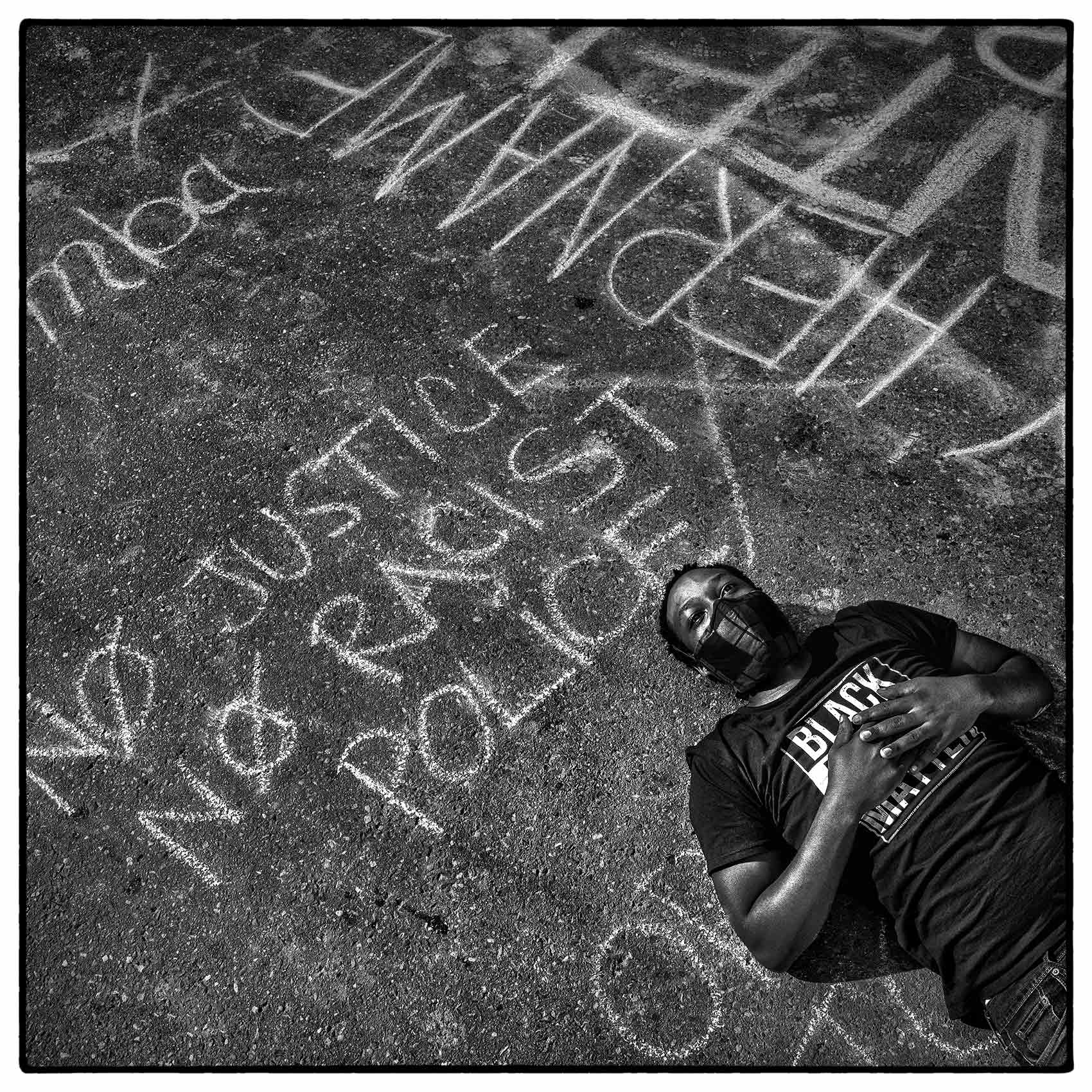 chalk written slogans surround a toronto black lives matter demonstrator as she lays on the street
