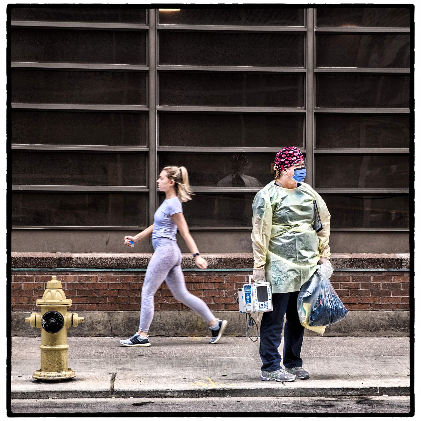 a young woman without a mask walks past a nurse wearing full ppe during the pandemic in toronto