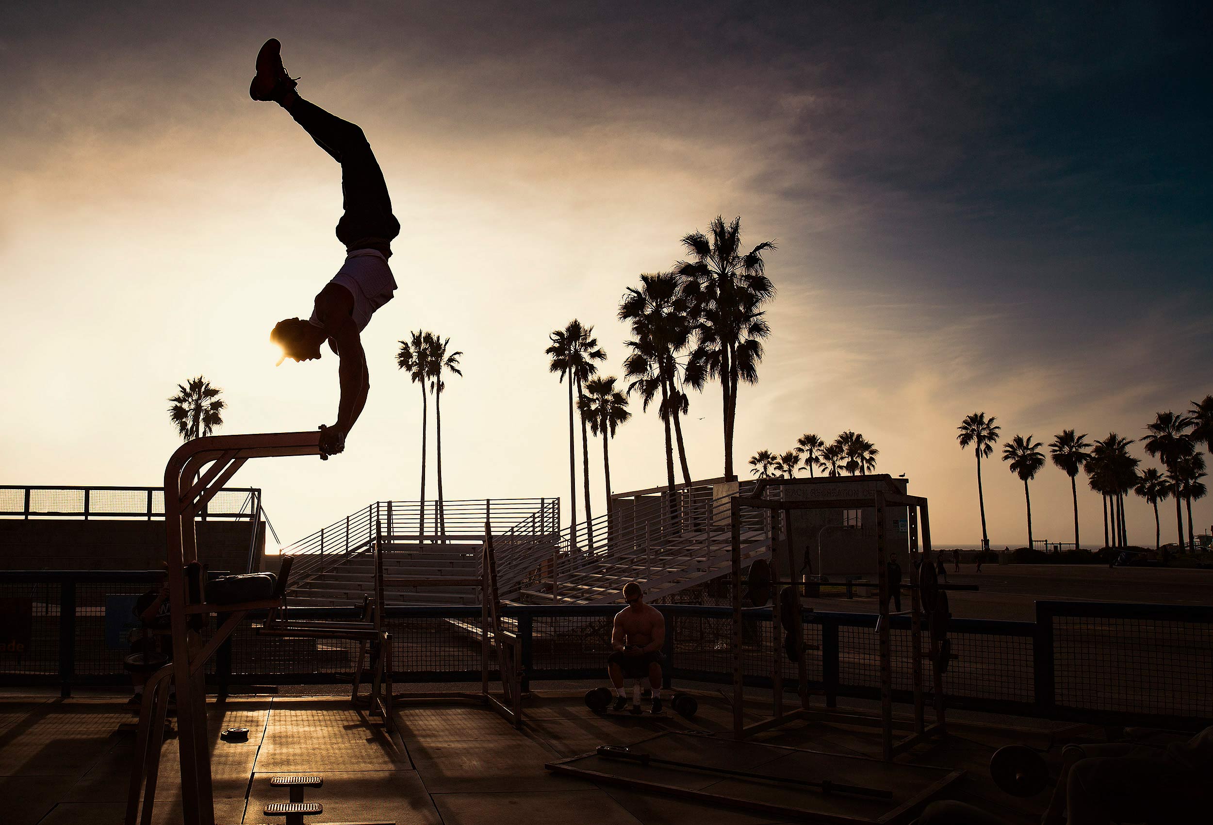 a man is sillhouetted working out at sunset on muscle beach in venice california