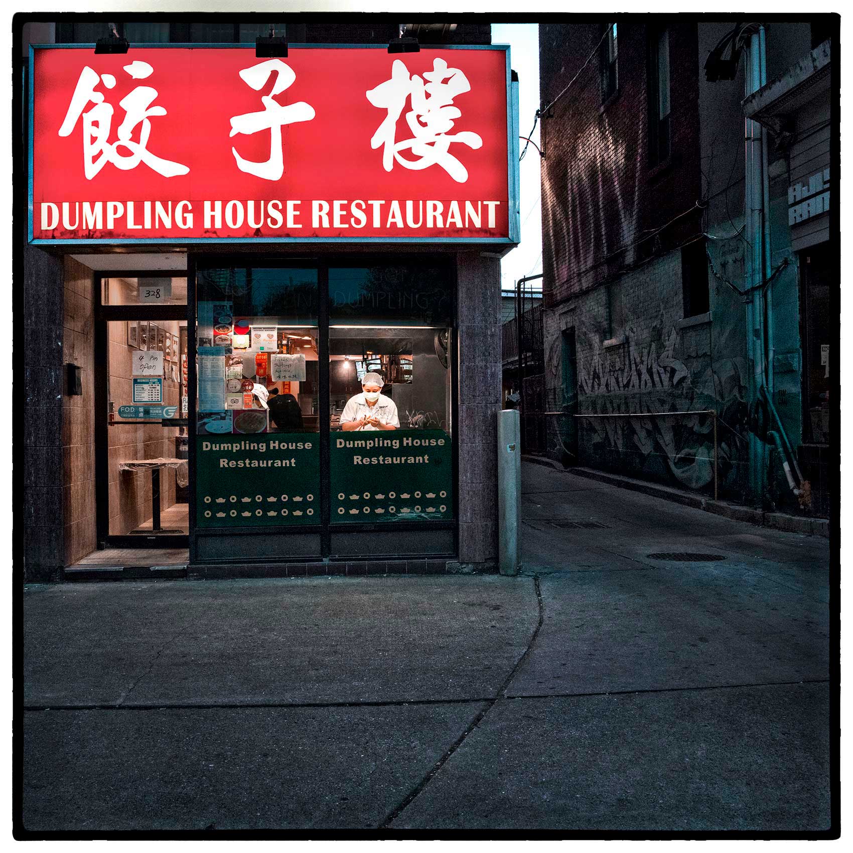 a cook wearing a face mask makes dumplings inside his toronto chinatown restaurant