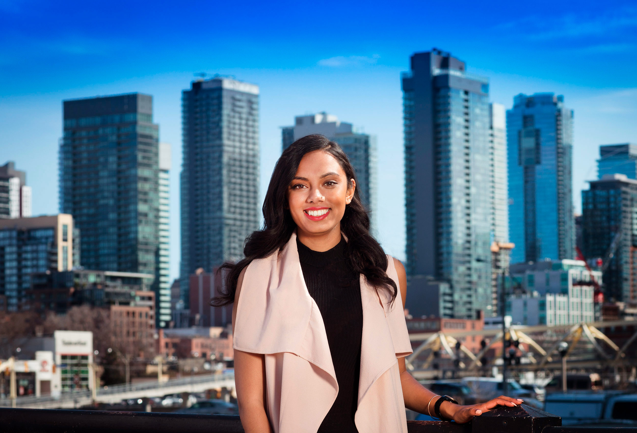 a toronto business executive stands in front of the toronto skyline posing for a corporate photo.