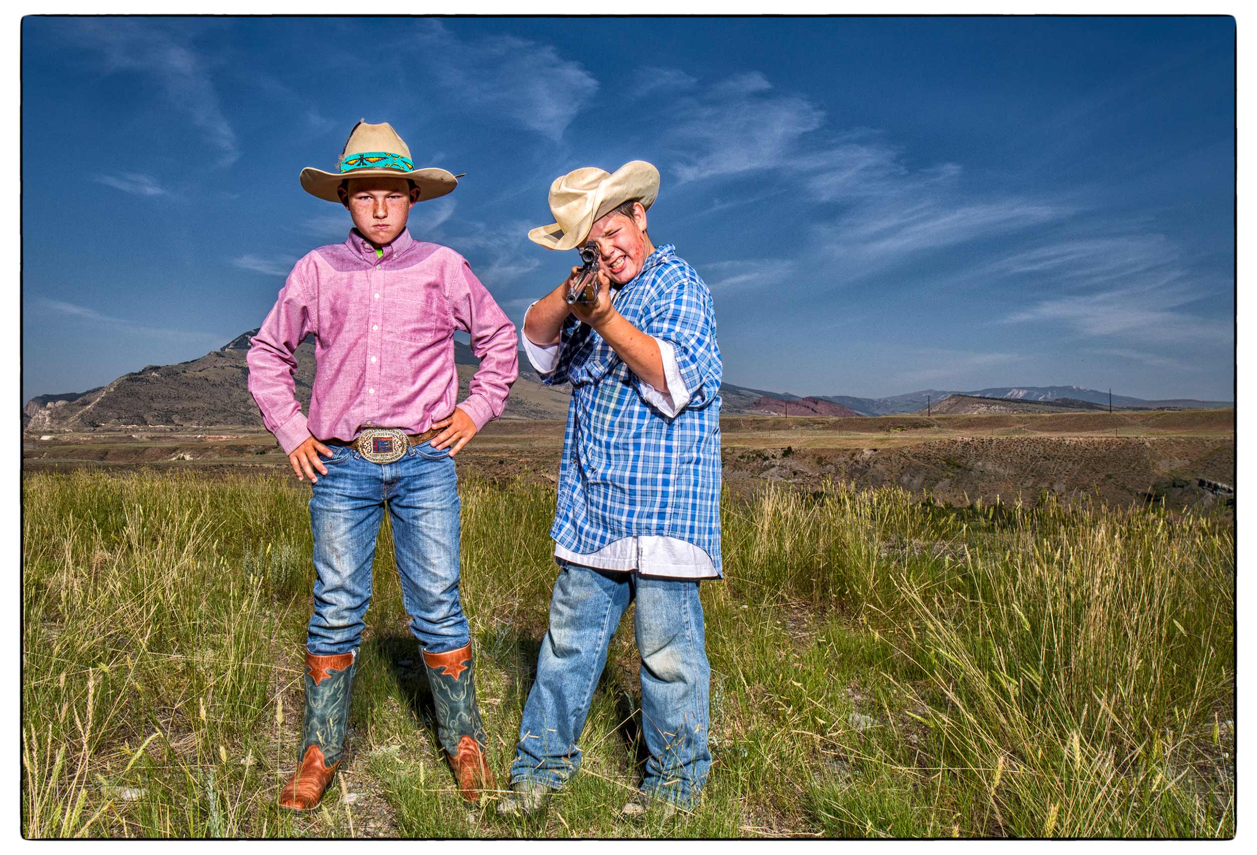 two-boys-one-with-a-rifle-point-it-at-the-photographer-during-a-portrait-in-cody-wyoming